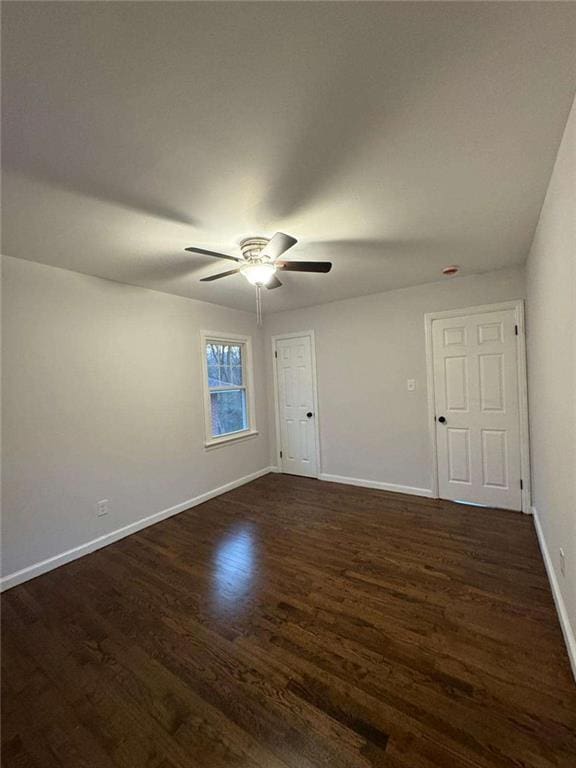 empty room with a ceiling fan, baseboards, and dark wood-style flooring