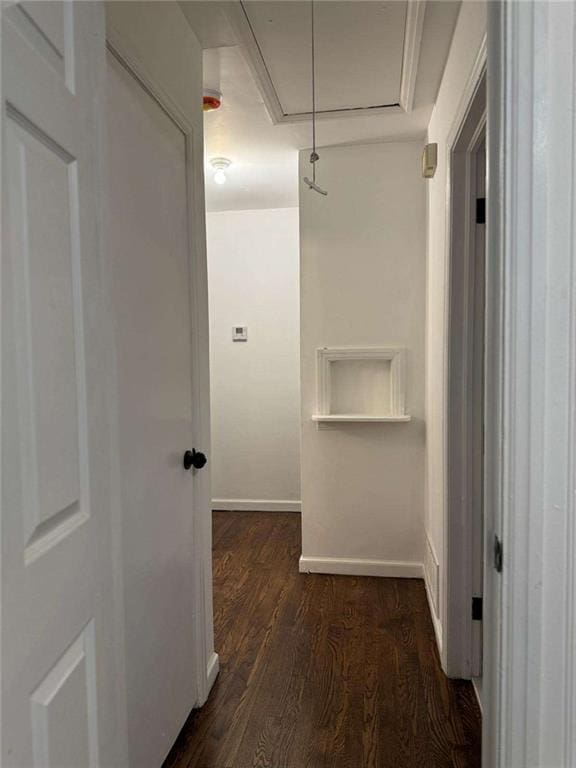 corridor with attic access, baseboards, and dark wood-style flooring