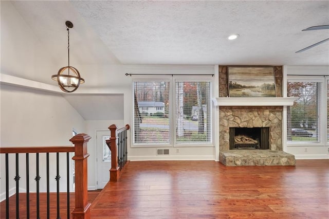 unfurnished living room with vaulted ceiling, dark hardwood / wood-style flooring, a fireplace, and a textured ceiling