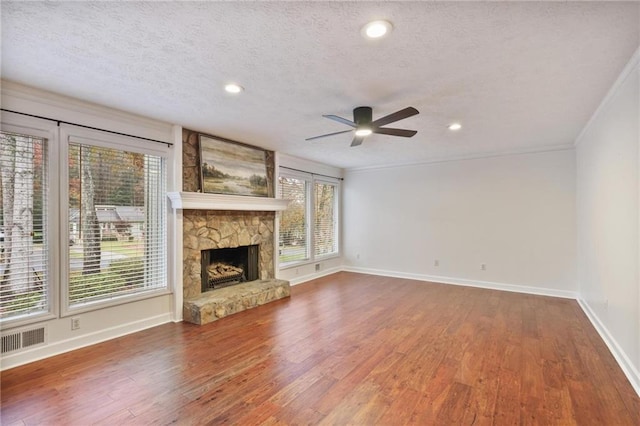 unfurnished living room with a healthy amount of sunlight, a stone fireplace, and a textured ceiling