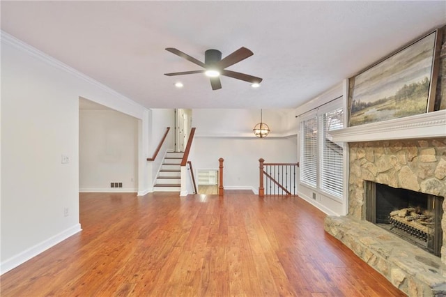 unfurnished living room with ceiling fan, crown molding, wood-type flooring, and a fireplace