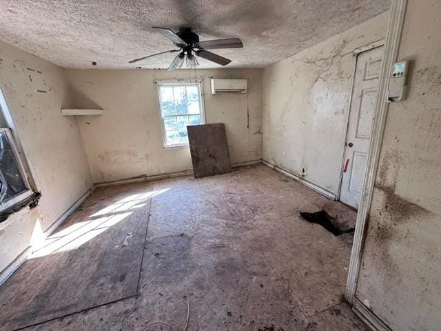 unfurnished room featuring a wall unit AC, a ceiling fan, and a textured ceiling