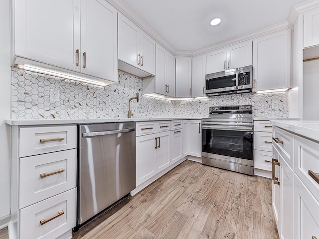 kitchen with light stone countertops, backsplash, stainless steel appliances, light hardwood / wood-style flooring, and white cabinets