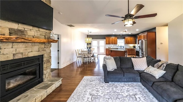 living room featuring ceiling fan, a fireplace, and dark hardwood / wood-style floors