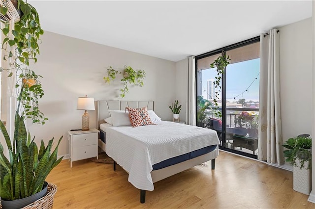 bedroom with expansive windows, access to exterior, and light wood-type flooring