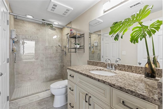 bathroom with a shower with door, vanity, and toilet