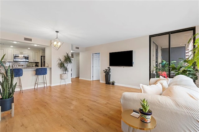 living room with an inviting chandelier and light hardwood / wood-style flooring