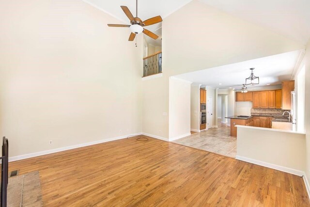 100 Bentwood Cir, Macon, GA 31210 - unfurnished living room with a sink, ceiling fan, light wood-style floors, baseboards, and high vaulted ceiling