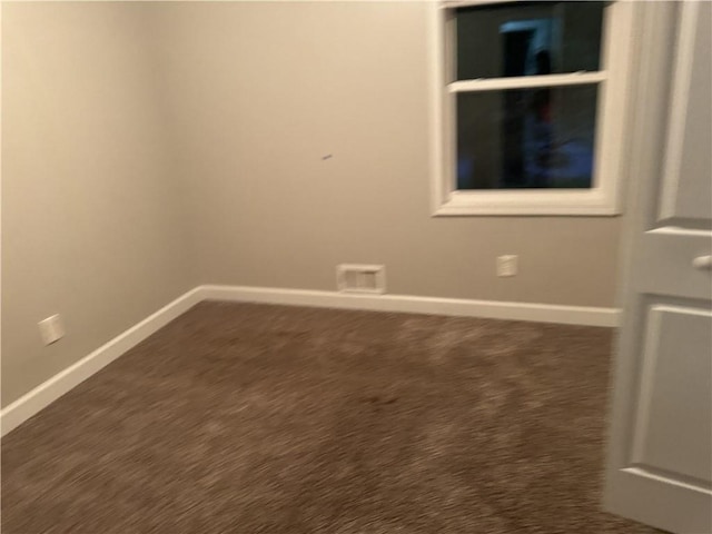 unfurnished room featuring baseboards and dark carpet