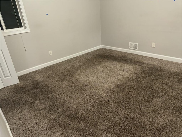 empty room with dark colored carpet and baseboards