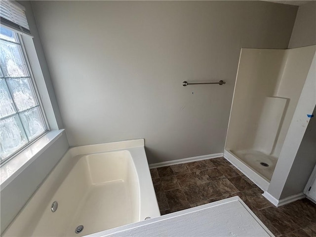 full bath featuring baseboards, plenty of natural light, walk in shower, and a bath