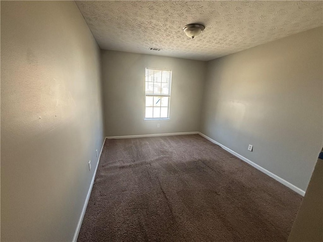 carpeted spare room with visible vents, baseboards, and a textured ceiling