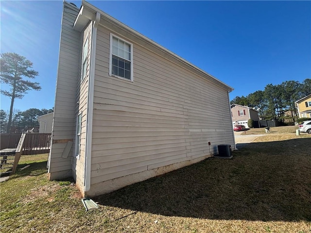 view of side of property featuring central air condition unit and a yard