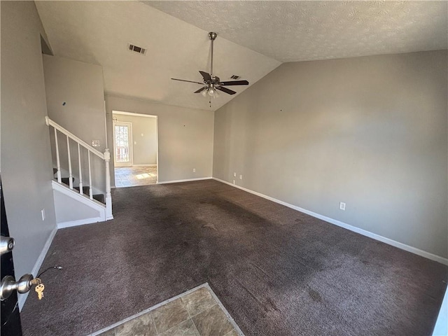 empty room featuring baseboards, visible vents, ceiling fan, stairs, and vaulted ceiling