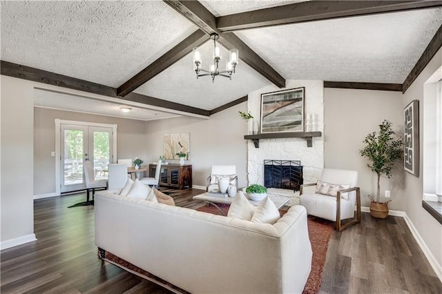 living room with a stone fireplace, lofted ceiling with beams, dark wood-type flooring, a textured ceiling, and an inviting chandelier