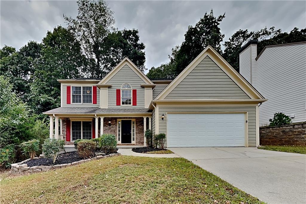 view of front of home featuring a front yard, covered porch, and a garage