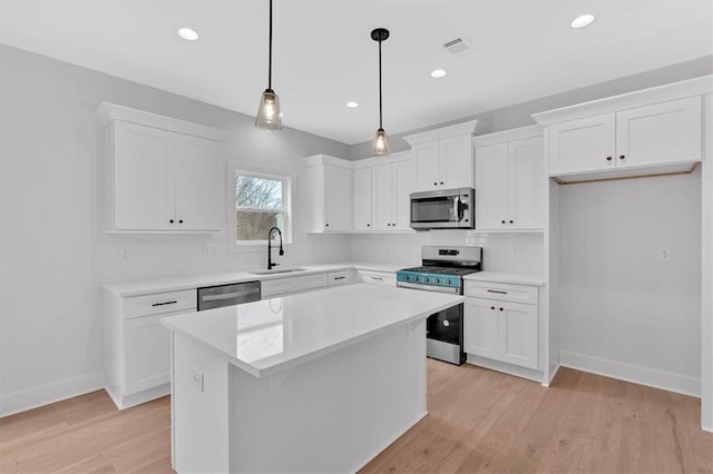 kitchen featuring white cabinets, pendant lighting, a center island, and stainless steel appliances