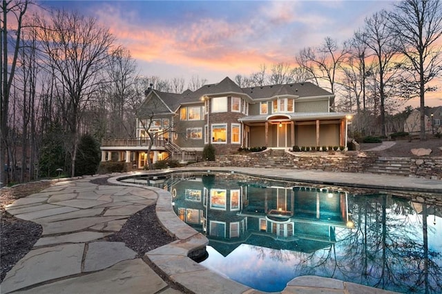 view of front facade featuring a garage, a chimney, a porch, and decorative driveway