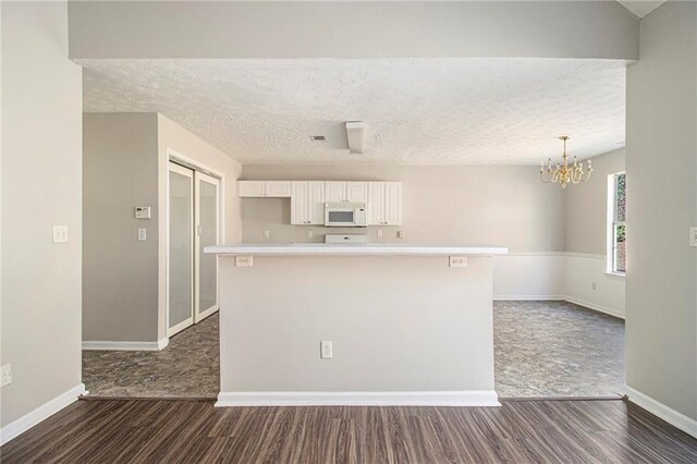 kitchen with white cabinets, a textured ceiling, dark hardwood / wood-style floors, and a notable chandelier