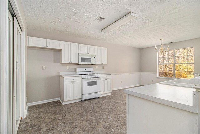 kitchen with white cabinets, hanging light fixtures, white appliances, and a notable chandelier