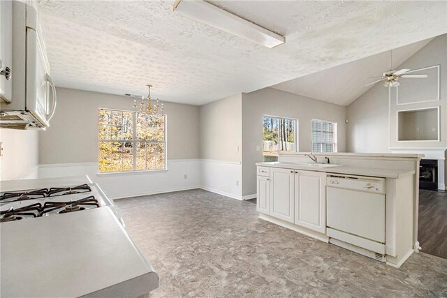 kitchen featuring plenty of natural light, white appliances, a textured ceiling, and lofted ceiling