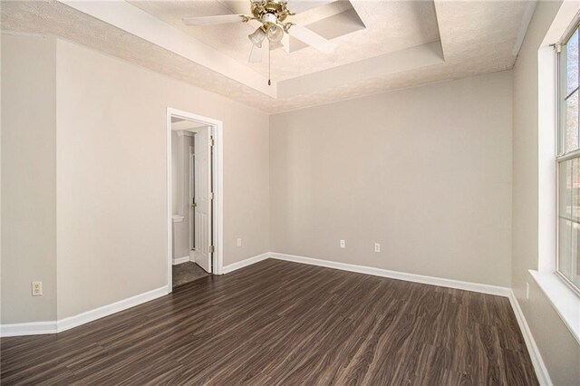 spare room with ceiling fan, dark hardwood / wood-style flooring, and a tray ceiling