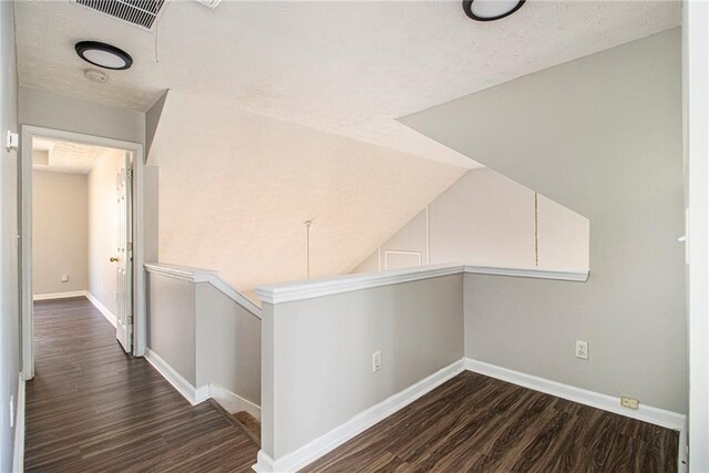 corridor with dark hardwood / wood-style floors and lofted ceiling