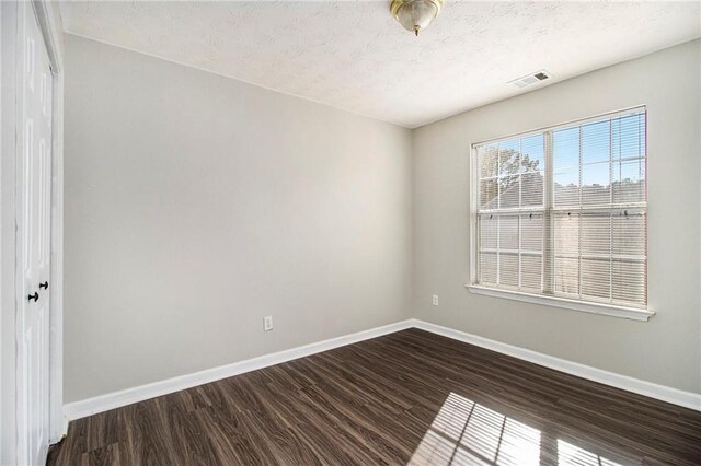 empty room with dark hardwood / wood-style flooring and a textured ceiling