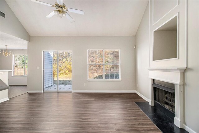 unfurnished living room featuring ceiling fan with notable chandelier, dark wood-type flooring, and lofted ceiling