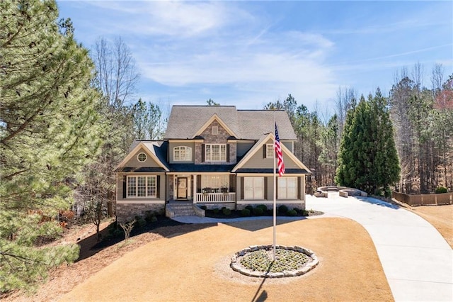 view of front of home featuring stone siding, covered porch, and dirt driveway