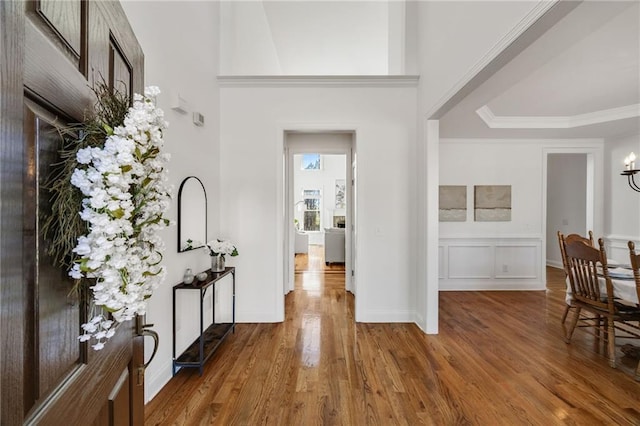 foyer with a notable chandelier, crown molding, baseboards, and wood finished floors