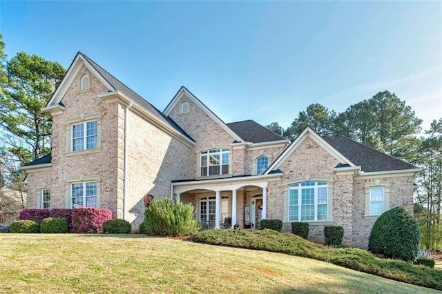 view of front of home featuring a porch, a front yard, and brick siding