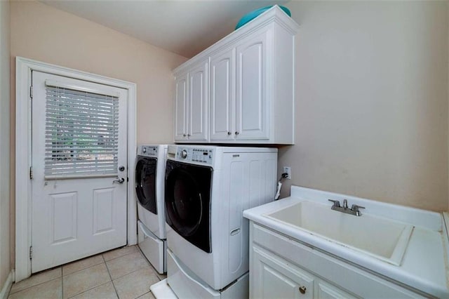 laundry area featuring light tile patterned floors, cabinet space, washer and clothes dryer, and a sink