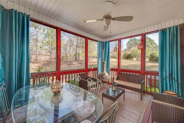 sunroom with outdoor dining space, wood finished floors, and ceiling fan