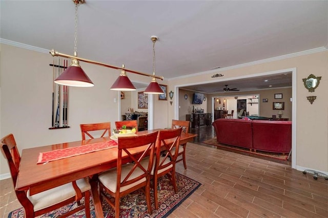dining room featuring baseboards, wood finished floors, ceiling fan, and crown molding