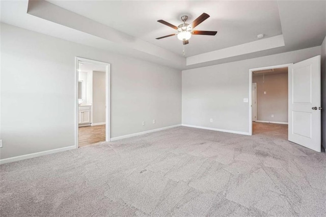 unfurnished bedroom featuring carpet floors, attic access, and a raised ceiling