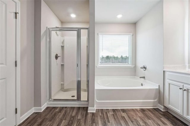 bathroom featuring wood finished floors, a garden tub, and a shower stall