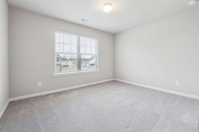 spare room featuring carpet floors, visible vents, and baseboards