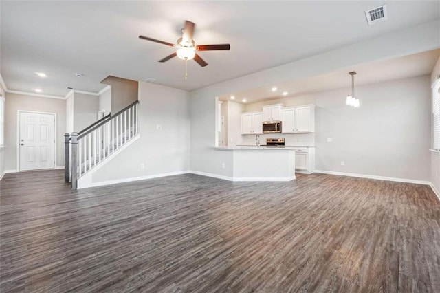 unfurnished living room featuring dark wood-style floors, crown molding, visible vents, stairway, and baseboards