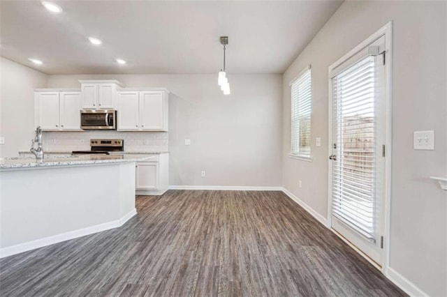 kitchen featuring dark wood-style floors, tasteful backsplash, appliances with stainless steel finishes, white cabinetry, and baseboards