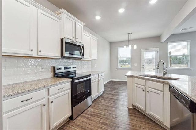 kitchen featuring stainless steel appliances, a sink, white cabinets, backsplash, and dark wood finished floors