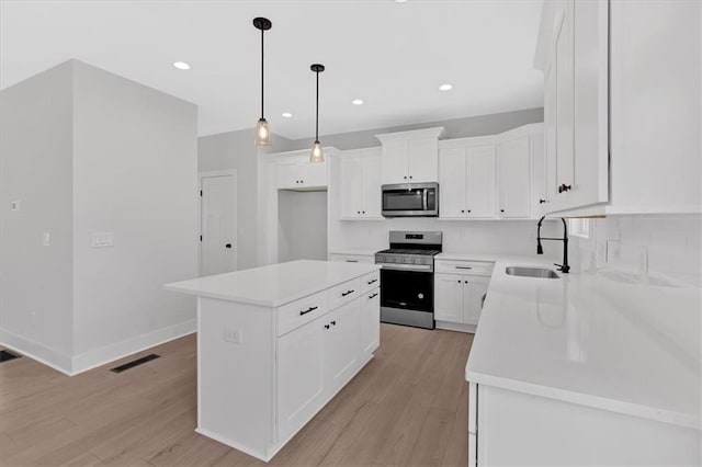 28 Creekview Dr SE, Cartersville, GA 30120 - kitchen with stainless steel appliances, a sink, light wood finished floors, white cabinets, and light countertops