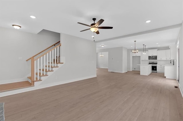 28 Creekview Dr SE, Cartersville, GA 30120 - unfurnished living room featuring a chandelier, a ceiling fan, a sink, light wood-type flooring, and baseboards