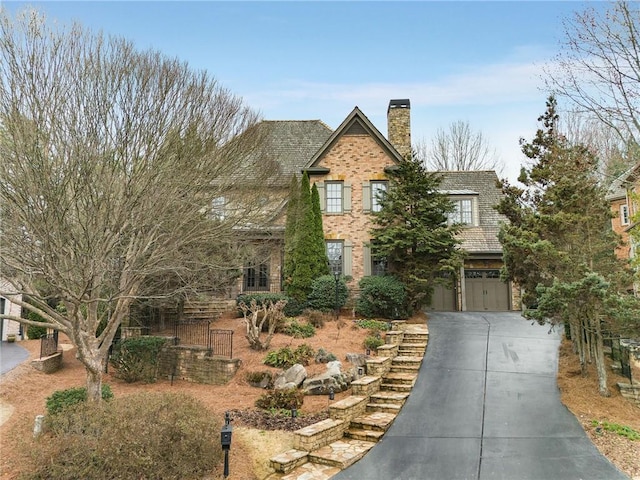 traditional-style house with concrete driveway, brick siding, a chimney, and an attached garage