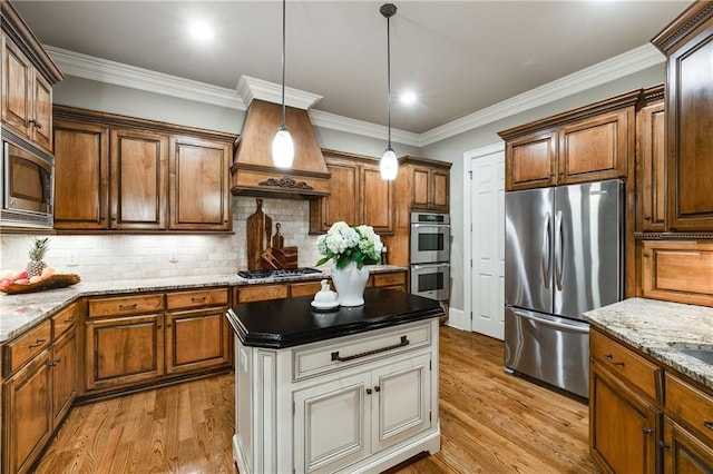 kitchen with appliances with stainless steel finishes, decorative light fixtures, light wood finished floors, and tasteful backsplash