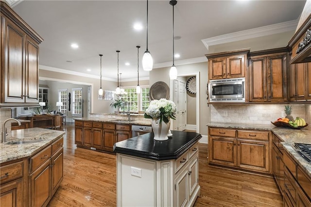 kitchen with stainless steel appliances, a center island, light wood-type flooring, and a sink