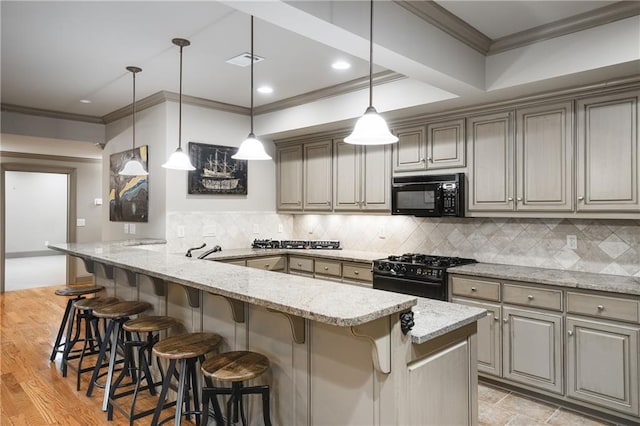 kitchen featuring a peninsula, visible vents, black appliances, a kitchen bar, and crown molding