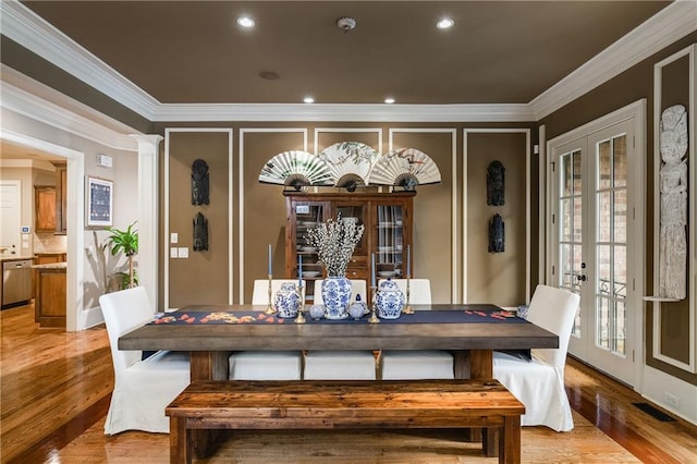 dining space with light wood finished floors, french doors, visible vents, and crown molding