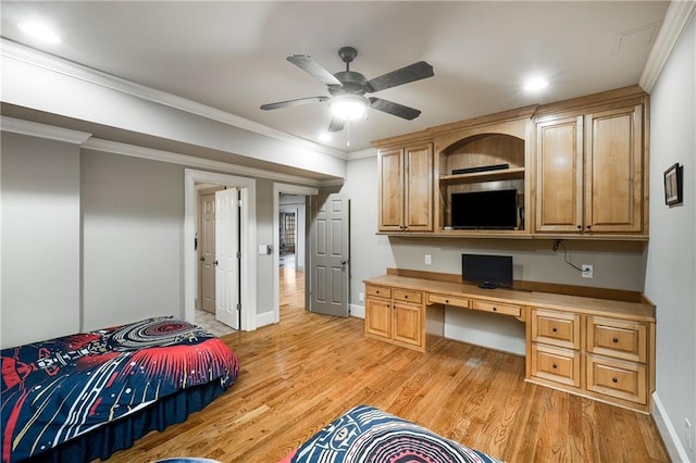 bedroom with baseboards, built in study area, crown molding, and light wood finished floors