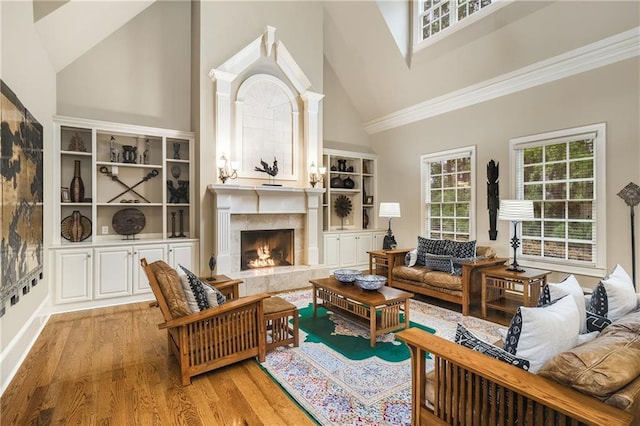 living room featuring light wood finished floors, high vaulted ceiling, ornamental molding, and a high end fireplace